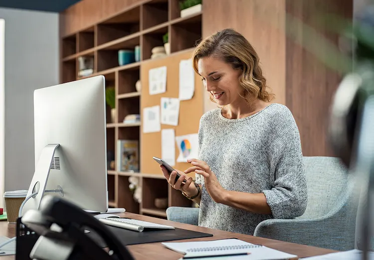 Woman at desk checks phone